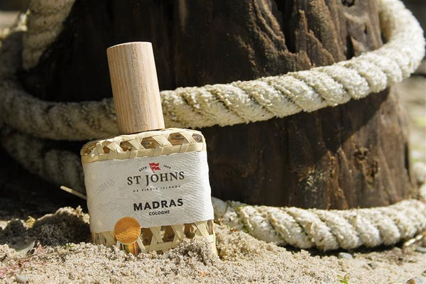 St Johns Madras Cologne bottle on sand with rope and wooden post background.