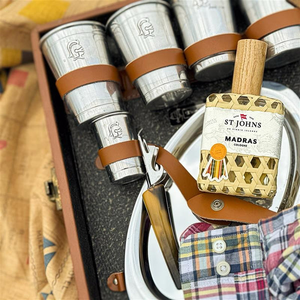 St Johns Madras cologne bottle resting on a travel bar set with plaid fabric.